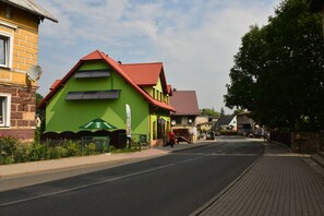 A street with a green building with a red roof, a yellow building, and a brick building.