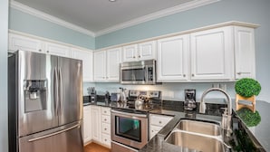 A modern kitchen with stainless steel appliances, white cabinetry, and a granite countertop. - Oceanfront Condo w/ Dual Balconies + Walk to Folly Pier (Folly Beach)