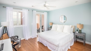 A bedroom with a bed, two bedside tables with lamps, a ceiling fan, and a view through a window with sheer curtains. - Oceanfront Condo w/ Dual Balconies + Walk to Folly Pier (Folly Beach)
