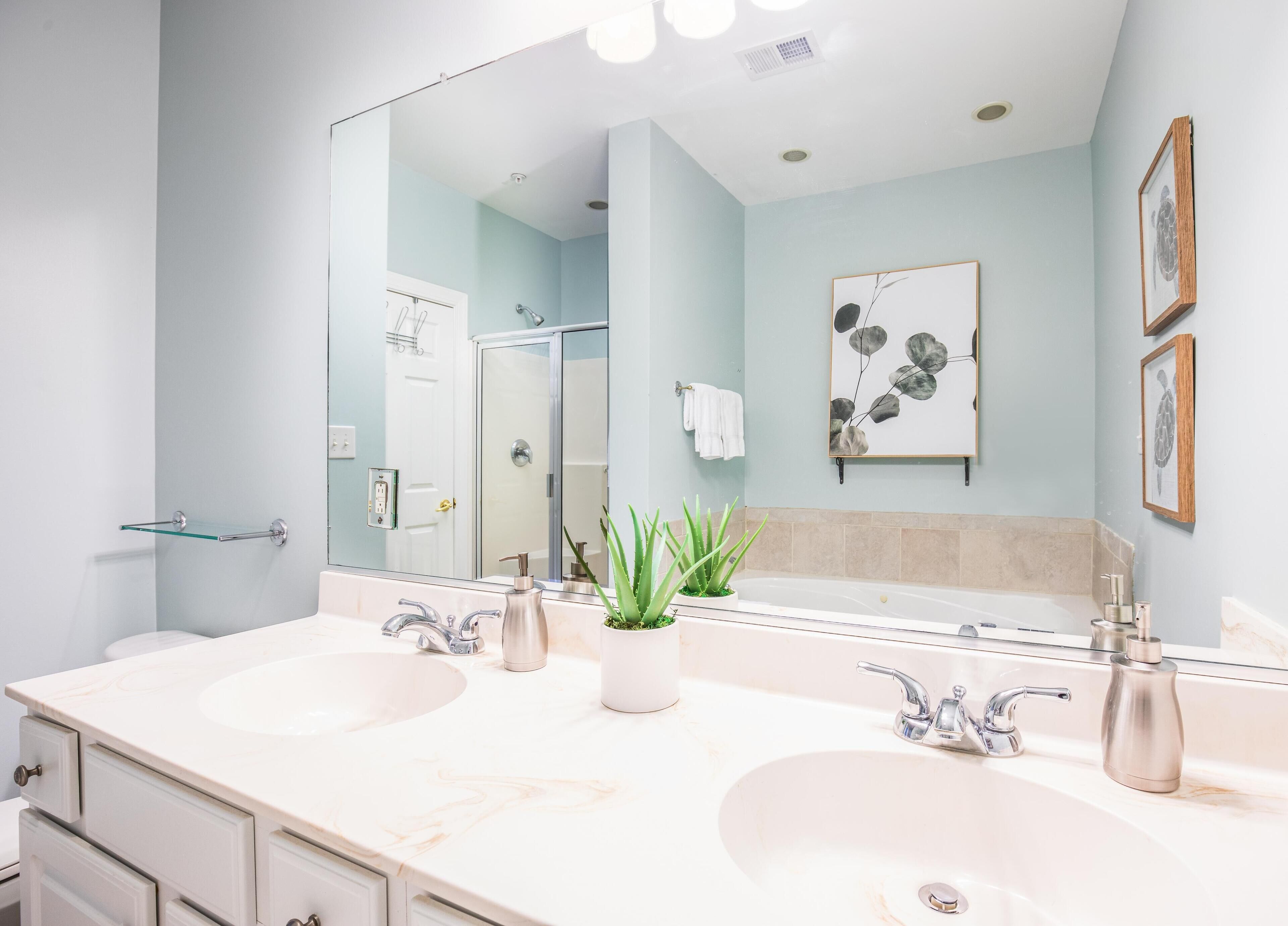Une salle de bain moderne avec deux lavabos, un grand miroir et une douche.