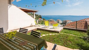 Una terraza con mesa lista para comer, sillas exteriores y vista al mar.