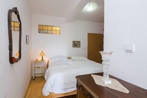 A bedroom with a bed, bedside table, lamp, and a mirror on the wall.