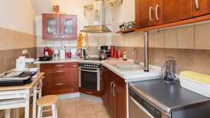 Una cocina moderna con armarios de madera, horno empotrado, lavavajillas y cafetera.