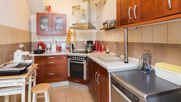 Una cocina moderna con armarios de madera, horno empotrado, lavavajillas y cafetera.