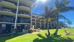 Un hotel de varios pisos con balcones, mobiliario exterior y palmeras.