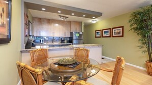 Una cocina moderna con armarios de madera, una mesa de comedor de vidrio y un refrigerador.