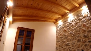 Un dormitorio con pared de piedra, techo de madera y cama con estructura metálica.