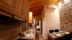 Una cocina con armarios de madera, pared de piedra y comedor con mesa dispuesta para cuatro.