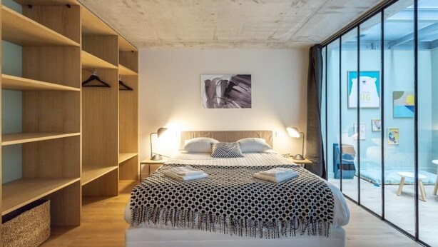 A modern bedroom with a large bed, wooden shelving, and a glass wall. - PHILIPPE AUGUSTE LOFT 1 - Loft for 12 - 5 rooms - BASTILLE - PÈRE LACHAISE (Paris)