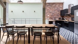 A modern kitchen with a brick backsplash, a dining area with a wooden table and chairs, and a skylight above. - PHILIPPE AUGUSTE LOFT 1 - Loft for 12 - 5 rooms - BASTILLE - PÈRE LACHAISE (Paris)