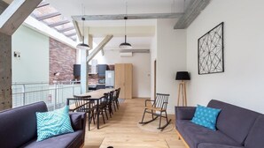 A modern living room with a dining area, a rocking chair, and a view of the city. - PHILIPPE AUGUSTE LOFT 1 - Loft for 12 - 5 rooms - BASTILLE - PÈRE LACHAISE (Paris)