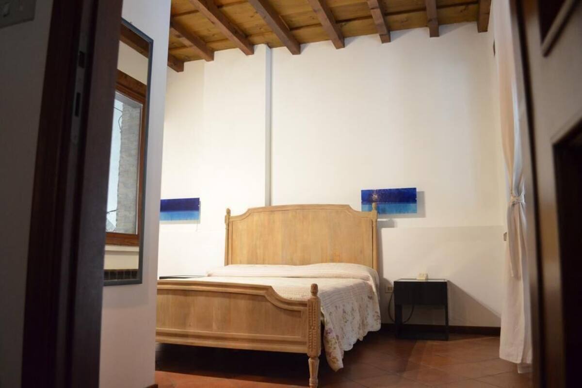Ein Schlafzimmer mit einem hölzernen Bett, einem Nachttisch und einer Wandleuchte.