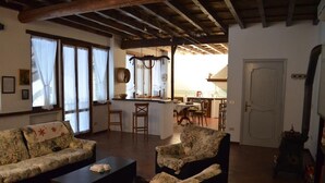 A living room with two sofas, a coffee table, and a kitchen in the background. - Agriturismo Cipolli e Podò Corte Carlini (Mantua)
