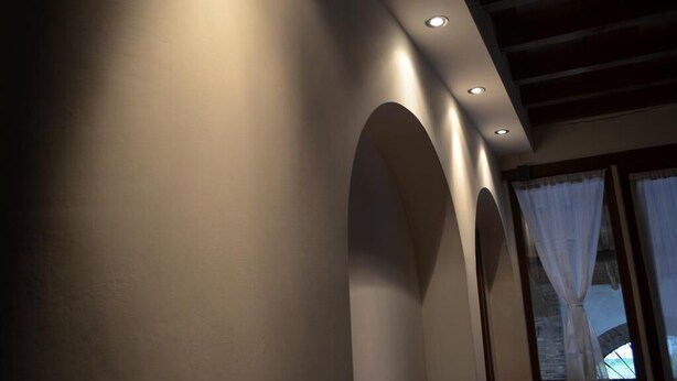 A modern interior with recessed lighting, arched alcoves, and a window with sheer curtains. - Agriturismo Cipolli e Podò Corte Carlini (Mantua)