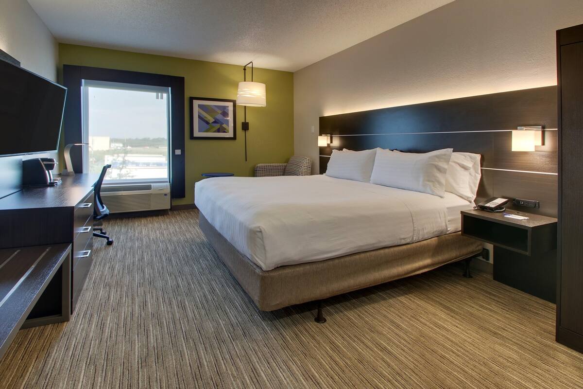 Ein Hotelzimmer mit Bett, Schreibtisch, Stuhl und einem großen Fenster.