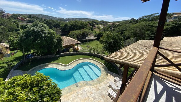 Blick auf einen Pool mit Fliesenverkleidung, umgeben von üppiger Vegetation und einer hügeligen Landschaft.