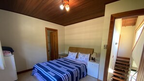 Ein Schlafzimmer mit einem Bett, einem Nachttisch, einer Lampe, einem kleinen Kühlschrank und einer Holztreppe.