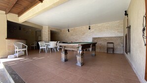 Ein Indoor-Erholungsbereich mit Billardtisch, Stühlen und einer Ziegelwand.
