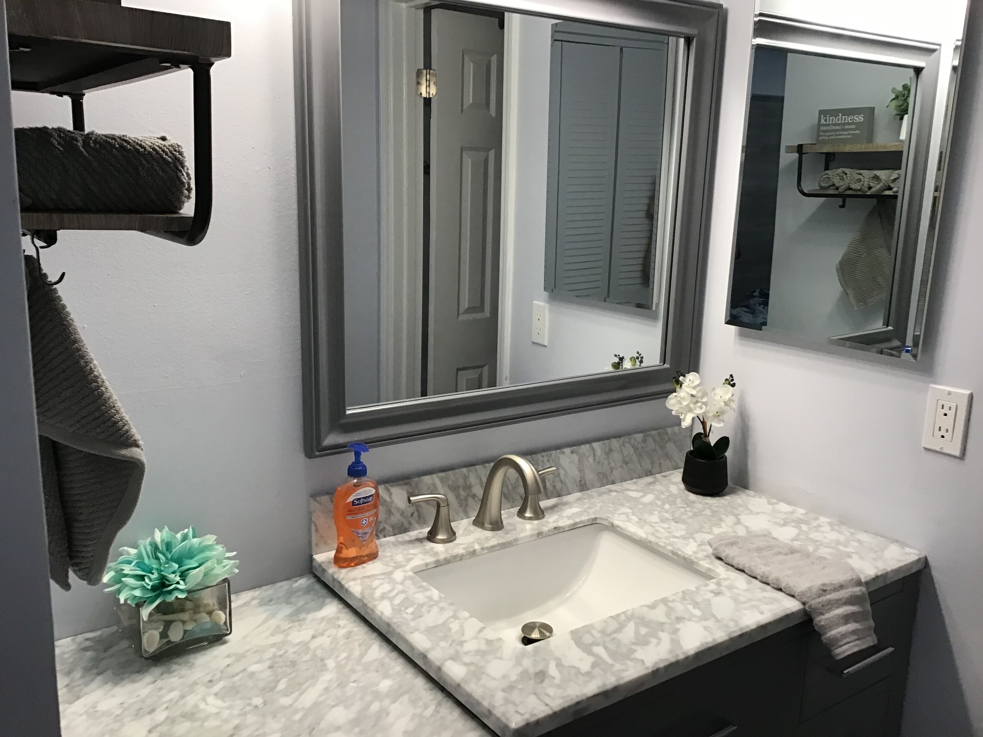 A bathroom with a large mirror, a sink, and a towel rack.
