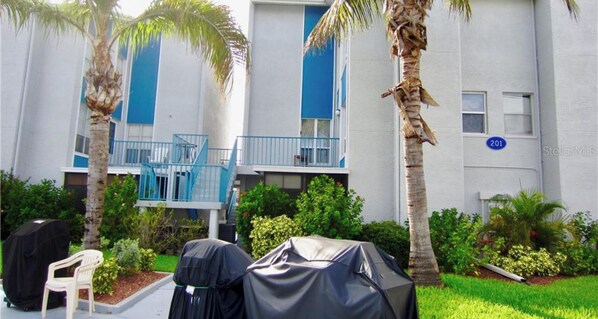 Residential building with a flat facade, featuring a balcony and outdoor seating area with grill.