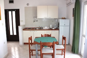 A compact kitchen with a dining table and chairs, a refrigerator, and a sink.