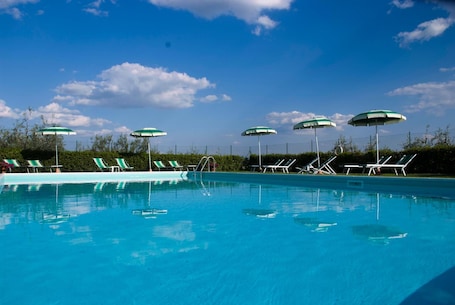 Una piscina al aire libre de temporada, sombrillas