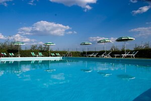 Una piscina con numerosi lettini e ombrelloni.