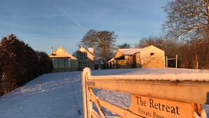 A wooden gate with a sign reading "The Retreat Private Property" leading to a snow-covered path and buildings. - The Retreat (Stroud)