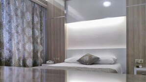 A modern hotel room with a large bed, a bedside table, a telephone, and a curtain. - Napa Otel (Denizli)