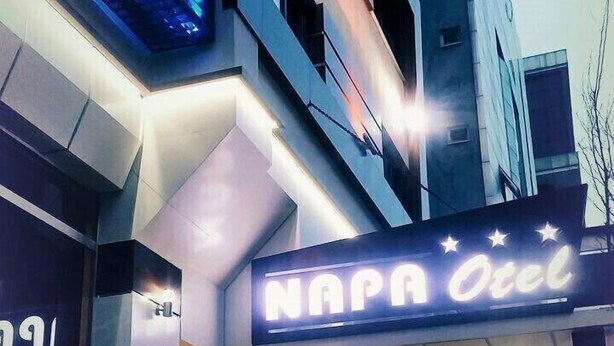 A modern building with a neon sign reading "NAPA Hotel" at the entrance. - Napa Otel (Denizli)