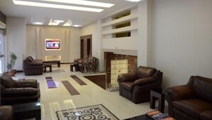 A modern living room with leather sofas, a fireplace, a flat-screen TV, and a ceiling with recessed lighting. - Napa Otel (Denizli)