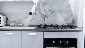 A kitchen with a gas stove, a toaster, and a microwave. There are three glasses on the counter.