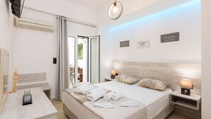 A modern hotel room with a large bed, bedside lamps, a wooden headboard, and a view of the outdoors. - Ocean Dream Suite (Mylopotamos)