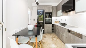 A modern kitchen with a black dining table, white chairs, and a built-in oven. - Ocean Dream Suite (Mylopotamos)