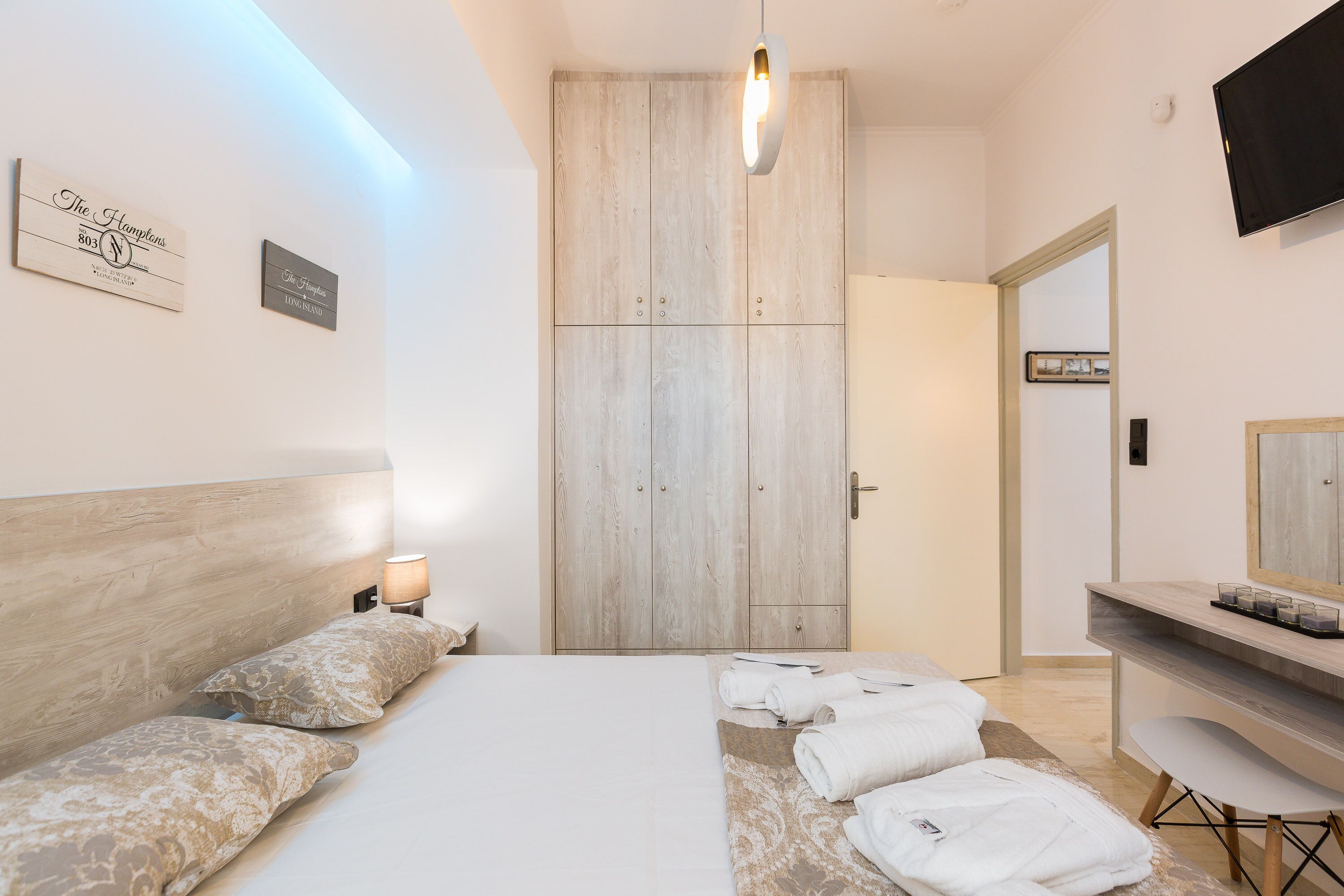 Um quarto moderno com cama, mesas de cabeceira, guarda-roupa, escrivaninha e espelho.