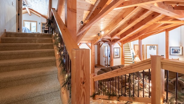 A wooden staircase with a railing, leading to a second floor with a view of the outside. - Spring Haven Home: Gorgeous, Dog Friendly (Breckenridge)