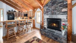 A rustic kitchen with wooden beams, a stone fireplace, and a bar area with stools. - Spring Haven Home: Gorgeous, Dog Friendly (Breckenridge)