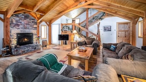 A spacious living room with a stone fireplace, wooden beams, a staircase, and a cozy seating area. - Spring Haven Home: Gorgeous, Dog Friendly (Breckenridge)
