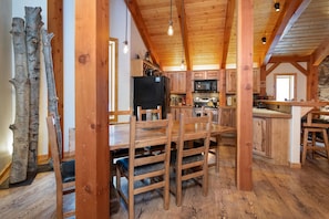 Un interior rústico de madera con comedor, cocina y pared de piedra.
