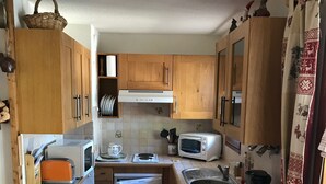 A compact kitchen with wooden cabinets, a built-in oven, a microwave, and a sink. - Accommodation at the foot of the ski slopes (La Giettaz)