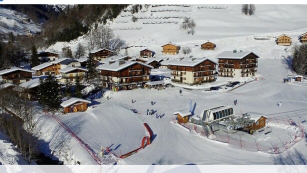 A ski resort with multiple wooden lodges, ski slopes, and a ski lift. - Accommodation at the foot of the ski slopes (La Giettaz)