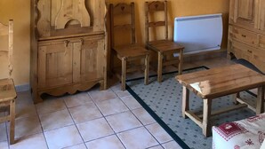 A room with a wooden cabinet, two chairs, a small table, a radiator, and a window with a view. - Accommodation at the foot of the ski slopes (La Giettaz)