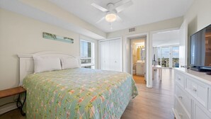 A bedroom with a bed, a ceiling fan, a window, and a view of the balcony. - Cozy Gulf Front Condo | Private Beach Access | Pool | Sleeps 8 (Gulf Shores)