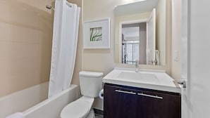 A modern bathroom with a bathtub, toilet, and sink. - 2 Bedroom/2 Bathroom Deluxe Suite (Toronto)