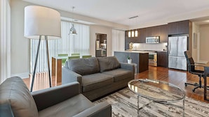 A modern living room with a sofa, a coffee table, and a dining area with chairs. - 2 Bedroom/2 Bathroom Deluxe Suite (Toronto)