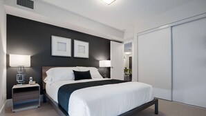 A modern hotel room with a large bed, bedside tables, a desk, and a wardrobe. - 1 Bedroom/1 Bathroom Suite (Toronto)