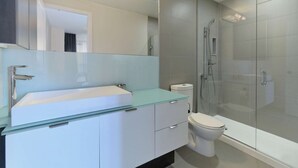 A modern bathroom with a glass-topped sink, a toilet, and a glass-enclosed shower. - 1 Bedroom/1 Bathroom Suite (Toronto)