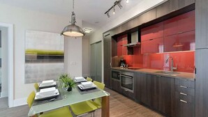 A modern kitchen with dark wood cabinets, a red backsplash, and stainless steel appliances. - 2 Bedroom/2 Bathroom Suite (Toronto)