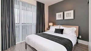 A hotel room with a large bed, dark curtains, a nightstand, and two framed pictures on the wall. - 2 Bedroom/2 Bathroom Suite (Toronto)