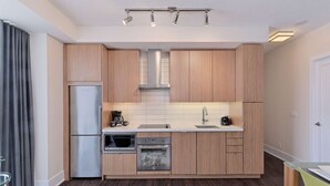 Une cuisine moderne dotée de meubles en bois, d’un réfrigérateur en acier inoxydable, d’un four à micro-ondes, d’un four traditionnel et d’une machine à café.